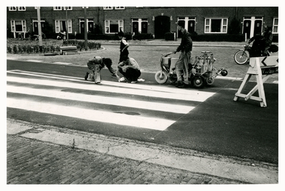 F006383 Met een handspuit wordt de verf van het zebrapad op het wegdek gespoten.