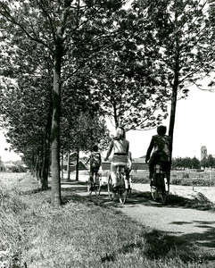 F013411 'Gezin' fietsend over het Meerpad langs de Trekvaart in IJsselmuiden, helemaal rechts de toren van de ...