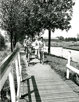 F013412 'Gezin' fietsend over het Meerpad nabij het bruggetje over de Trekvaart in IJsselmuiden, helemaal rechts de ...