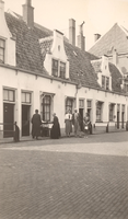 F000507 Bewoners voor hun huisjes op de binnenplaats van de Gast- en Proveniershuizen aan de Burgwal.