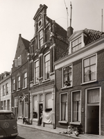 F000161 Viertal woonhuizen met de huisnummers 96 t/m 104 in de Boven Nieuwstraat, op nr. 100, (met vlag) de winkel van ...