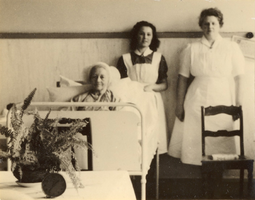 F000529 Één der bewoners en 2 verpleegsters in de ziekenzaal van de Gast- en Proveniershuizen aan de Burgwal.