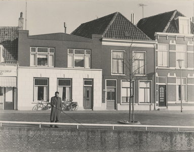 F000432 Man staat de vissen in de stadsgracht de Burgel, op de achtergrond de woningen aan de Burgwal met de nrs. 119 ...