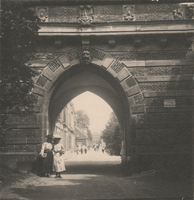 F000646 Twee jongedames poseren bij de doorgang van de Cellebroederspoort met een doorkijk naar de Cellebroedersweg.