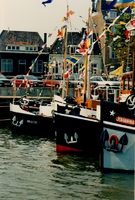 F011659 Versierde sleepboten liggen naast elkaar afgemeerd voor de kade.