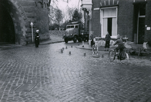 F011014 Op de hoek Cellebroedersweg met de 2e Ebbingestraat regelt een politieagent het verkeer, links de doorgang van ...