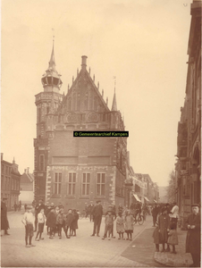 F001318 Een groep kinderen poseert voor de fotograaf bij de zijgevel van het Oude Raadhuis met de Schepentoren, links ...