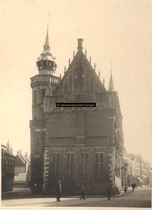 F001319 Een man en twee kinderen poseren voor de fotograaf bij de zijgevel van het Oude Raadhuis met de Schepentoren, ...