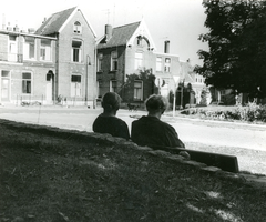 F000916 Foto 1: Twee dames op een bankje kijken in de richting van de woningen aan de 1e Ebbingestraat nr. 31 en nr. ...