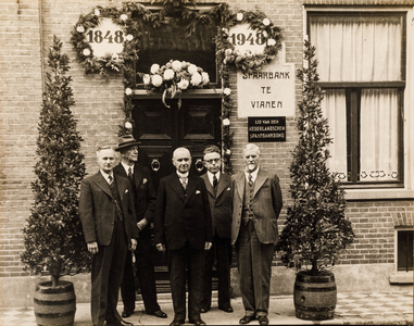  Groepsfoto van het bestuur van de Spaarbank te Vianen, staande voor de deur van het kantoor, ter gelegenheid van het ...