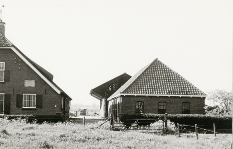 Rechter gedeelte van boerderij, rechts daarvan een schuur met schilddak, daarachter een open loods.