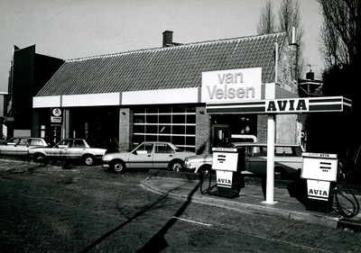  Garagebedrijf Van Velsen. Op de voorgrond enkele personenauto's en een tankstation met twee Avia benzinepompen.