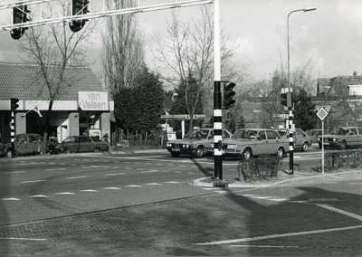  De Stationsweg ter hoogte van de kruising met de Molenweg/Dorpsstraat. Enkele auto's staan voor het verkeerslicht. ...