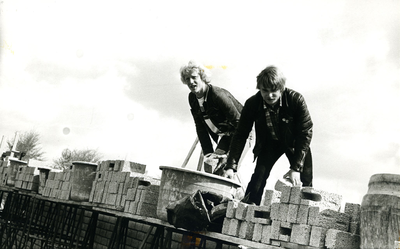  Twee leerling-bouwvakkers in actie tijdens de bouw van de sporthal.