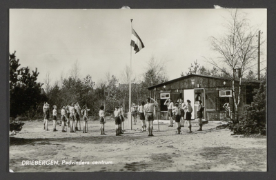  Een groep padvinders rond de vlag voor het houten clubgebouw.