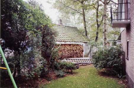  Zijkant huis met opgestapeld hout.