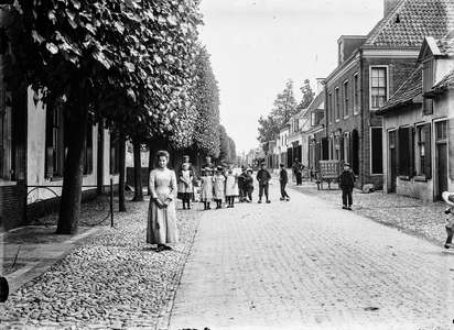  De Voorstraat met bebouwing en leilinden te Woudenberg, uit het westen met groep kinderen.