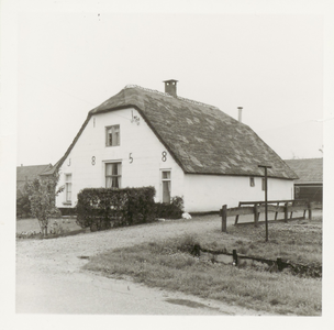  De witgepleisterde boerderij met rieten dak. Het jaartal 1858 is gemaakt van sierankers.