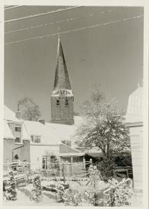  De toren van de NH kerk en daarvoor de achterzijde van de huizen aan de Brink, overdekt met sneeuw.
