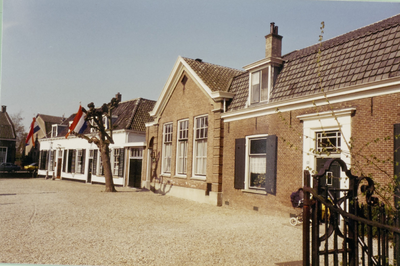  Het gemeentehuis met vlaggen ter gelegenheid van Koninginnedag en 2 andere gebouwen.