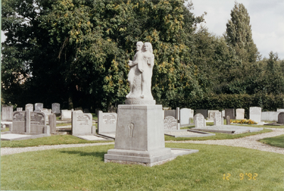  De begraafplaats achter de kerk met een monument met een man en een vrouw erop.