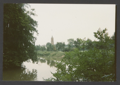  Water omgeven door veel bomen en overige beplanting, in de verte de toren van de St. Andrieskerk.