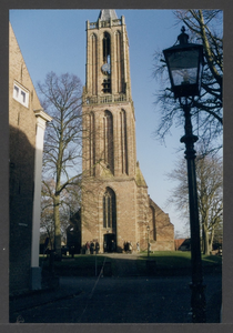  De toren van de St. Andrieskerk. Bij de entree enkele kerkgangers.