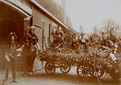  Groepsfoto van verklede mannen en jongens op en bij een wagen en een paard ter gelegenheid van Koninginnedag te Amerongen