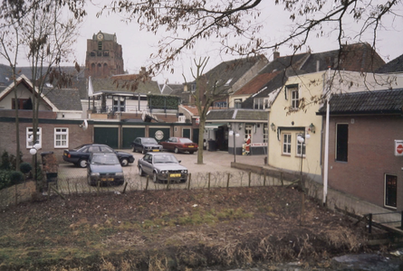  Gezicht op de parkeerplaats naast het pand, met op de achtergrond garages, daken en de kerktoren.