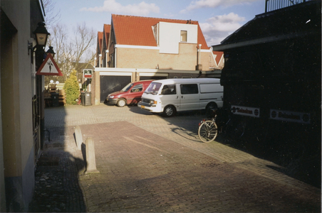  Close-up van enkele geparkeerde busjes en fietsen achter het pand.