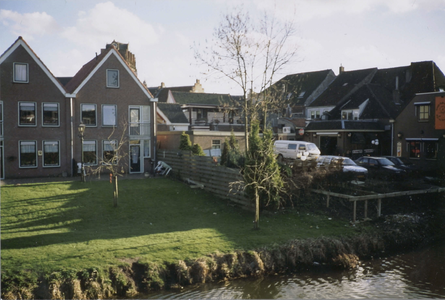  Links zijn enkele nieuwbouwwoningen zichtbaar, rechts het parkeerterrein achter het pand.