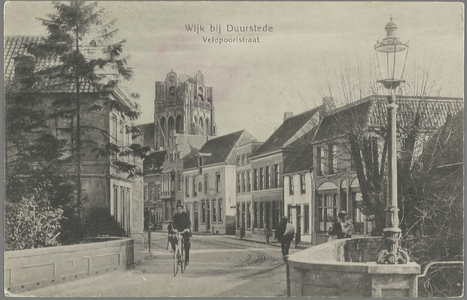  Gezicht op de brug en de straat in, met daarin een fietser, een wandelaar en een vrouw met een kind op de arm. Het zou ...