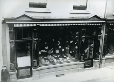  Hoeden- en herenkledingzaak van W.F.J.G. van Bekkum (zie de naam op de glazen winkeldeur). Op de winkelruit staat: ...