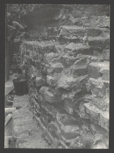  Twee bouwvakkers staan bij een stuk grof gemetselde stenen van een muur van de toren.