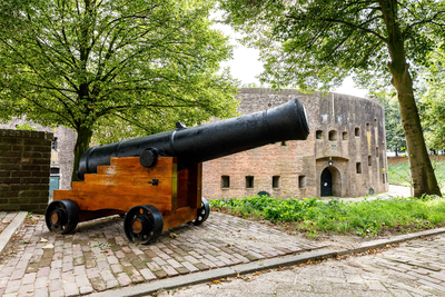  Een scheepskanon ter versiering op Fort Honswijk. Op de achtergrond de bomvrije toren
