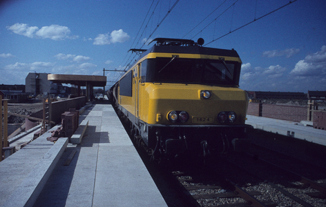  Een goederentrein passeert het station in aanbouw.