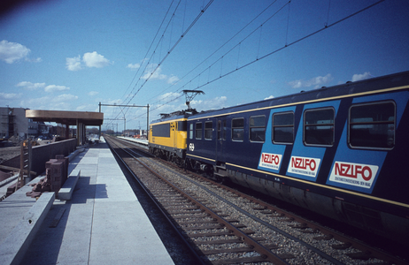  Een trein richting Utrecht passeert het station in aanbouw.