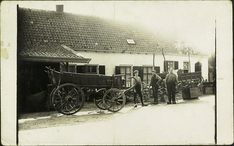  De smederij en woningen aan de zuidzijde van het Plein. Op de voorgrond boerenwagens en de drie mannen van de smederij.