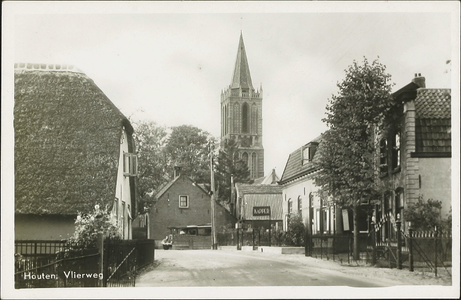 Gezicht op de toren van de nederlands-hervormde kerk vanaf de Vlierweg met rechts een gedeelte van het pand Vlierweg 3.