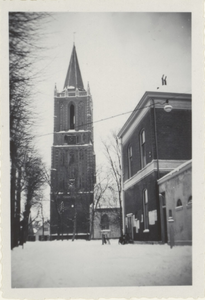  De toren van de nederlands-hervormde kerk en de rechtergevel van het gemeentehuis in de sneeuw.