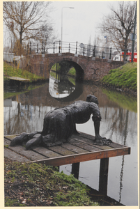  Het beeld van de wasvrouw aan de Schalkwijksewetering met op de achtergrond de Brinkbrug.