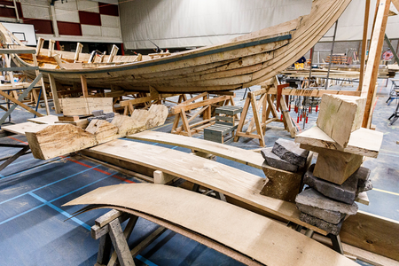  Vordering bouw schip met op de voorgrond het buigen van planken voor de romp. De plank wordt nat gemaakt en gebogen ...